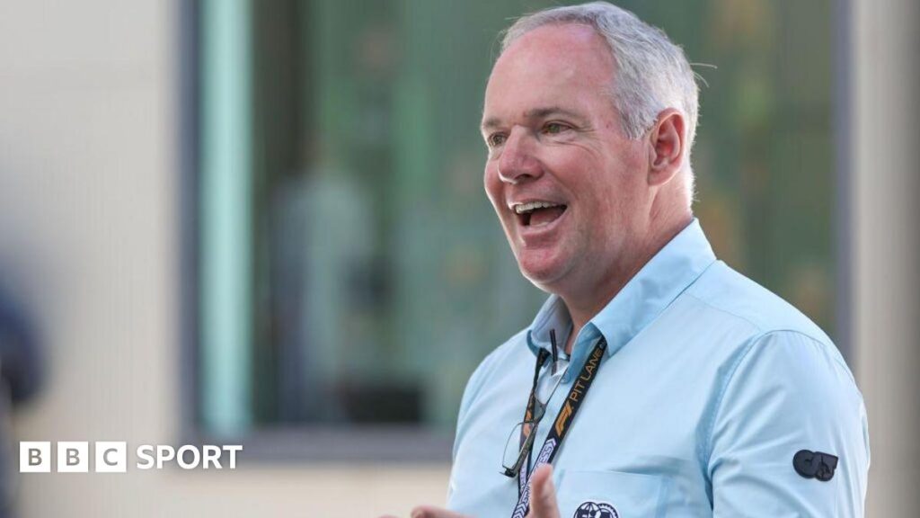 Tim Mayer smiling while wearing an FIA-branded long-sleeved shirt